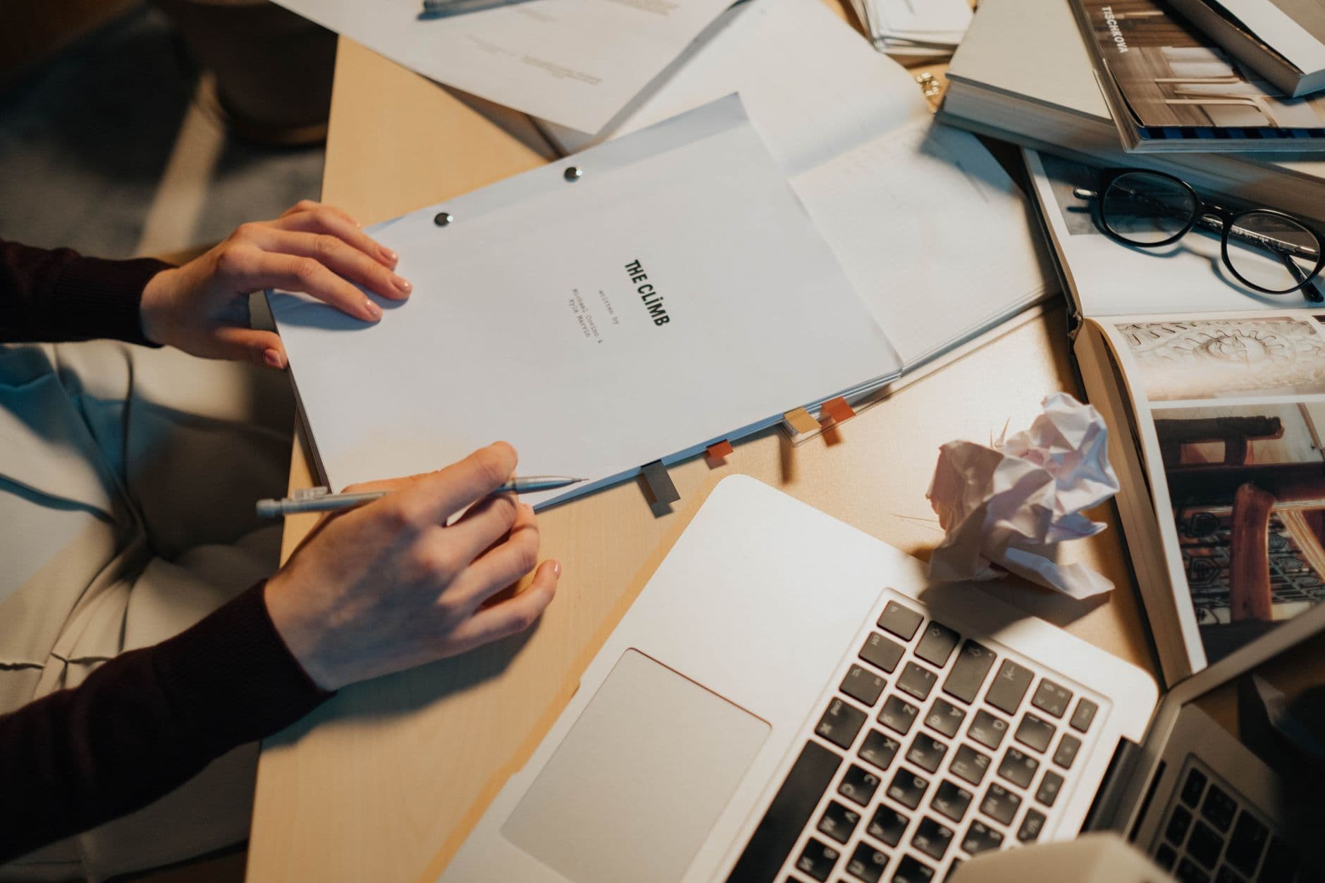 Person reviewing research notes beside a laptop and documents