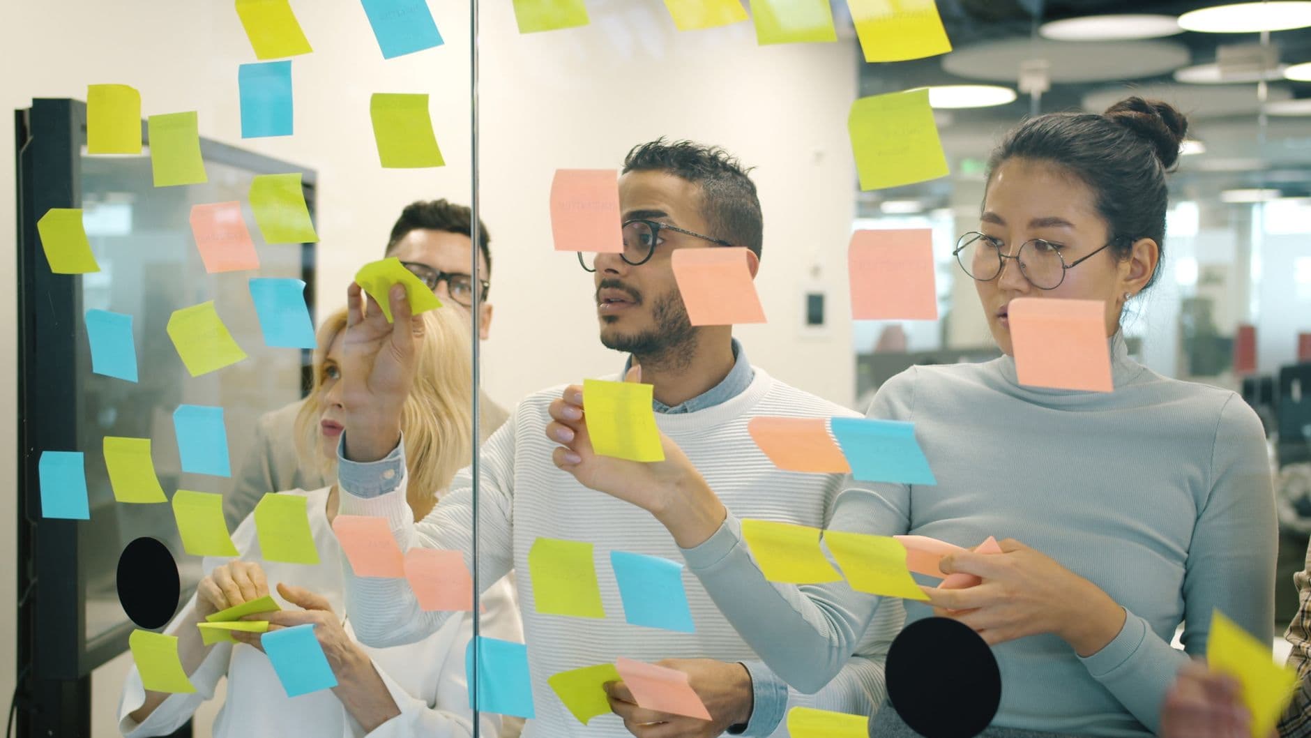 Colleagues planning a workflow with sticky notes on a board